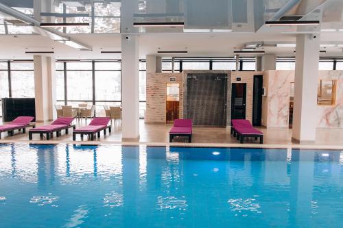 布克维Kasimir Resort Hotel & SPA的一座建筑中带紫色椅子的游泳池