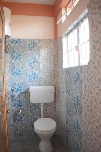 乞拉朋齐Metianil Homestay的浴室设有白色卫生间和蓝色瓷砖。