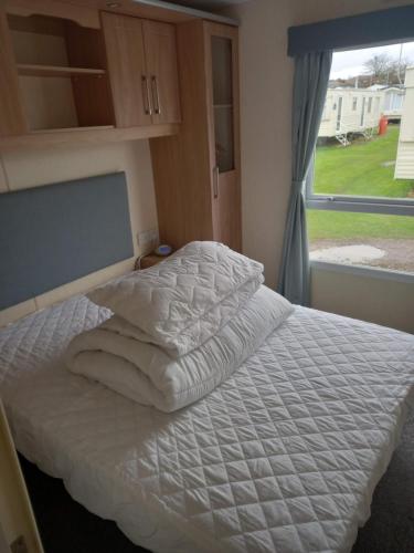 亨斯坦顿Sunny Hunny Manor Park Caravan的卧室配有白色床单和窗户