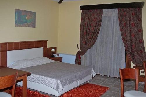 Mikrós PrínosTSIGOURA VERDE RESORT的一间卧室配有一张床、一张桌子和一个窗户。