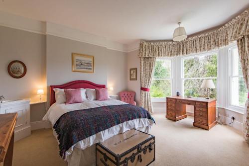 查林Burleigh House by Bloom Stays的一间卧室配有一张床、一张书桌和一个窗户。