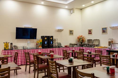 圣路易斯Hotel Santos Dumont Aeroporto SLZ的一间带桌椅和电视的用餐室