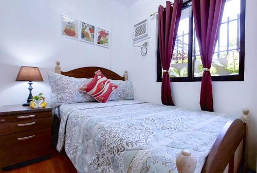 Liloan2 Bedroom Apartment ~ 5 Minutes to Grand Mall的一间卧室配有床和红色窗帘的窗户