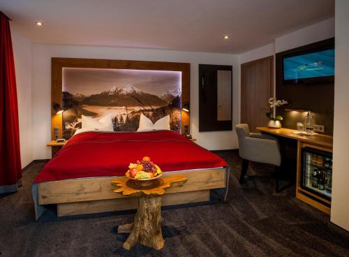 柯尼希斯湖畔舍瑙布鲁奈克阿本酒店的一间卧室配有一张红色大床和一张书桌
