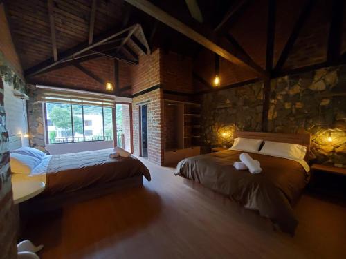 巴尼奥斯La Quinta Mansión Lofts的一间卧室设有两张床和石墙