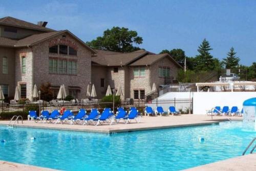 布兰森Luxury Family Condo w/ Great Views & Entertainment的一座带蓝色椅子的游泳池和一座建筑