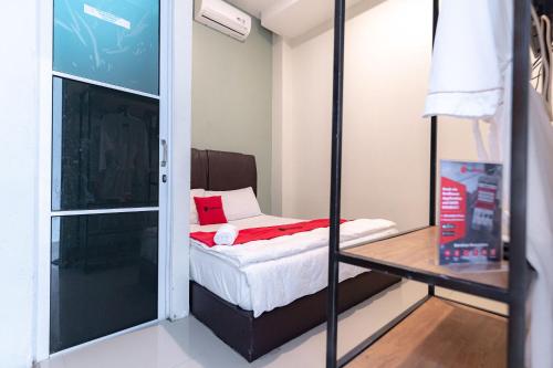 秾莎RedDoorz near Hang Nadim Batam Airport的小房间,设有床和玻璃门