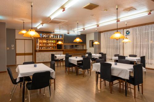 信浓Elan Hotel Lake Nojiri的用餐室配有白色的桌椅和灯光