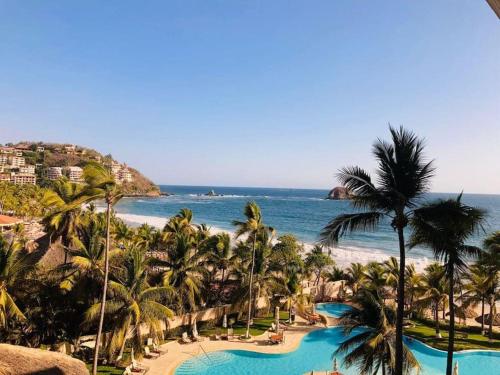 伊斯塔帕Condominio en Ixtapa frente a la playa的享有棕榈树度假村和大海的景致。