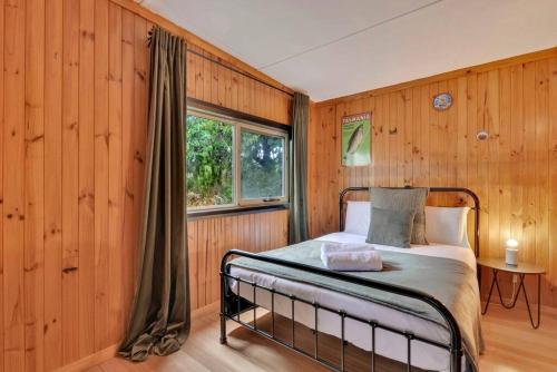 圣海伦斯Parnella Hideaway的一间卧室设有木墙和一张带窗户的床