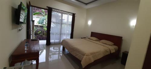 沙努尔Kubu doble的一间卧室配有一张床、一张书桌和一个窗户。