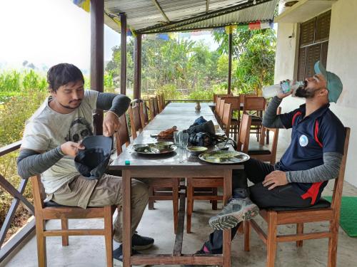 BhurkīāBardiya Eco Safari Homestay的坐在桌子上的两个人,从水瓶里喝了水