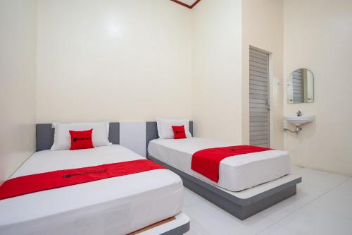 SolokRedDoorz Syariah near RS Tentara Solok的白色客房的两张床,配有红色枕头
