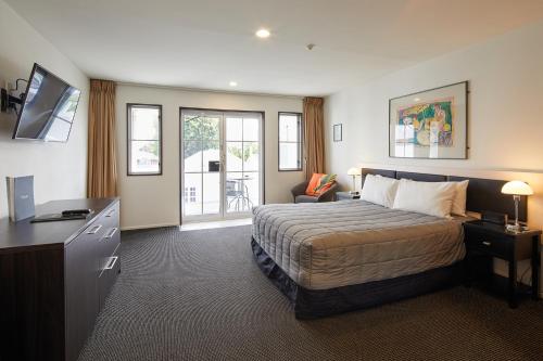 基督城帕威林酒店的一间卧室配有一张床、一张书桌和一台电视