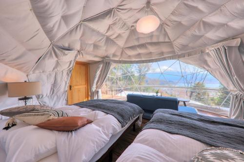 富士河口湖Retreat Camp Mahoroba的一个带窗户的帐篷内一间卧室,配有两张床
