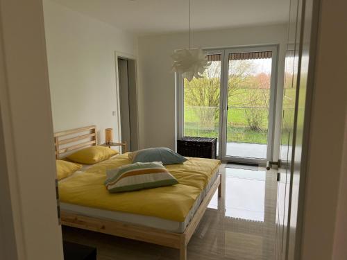 EselbornRésidence du Golf Eselborn的一间卧室配有一张带黄色床单的床和一扇窗户。