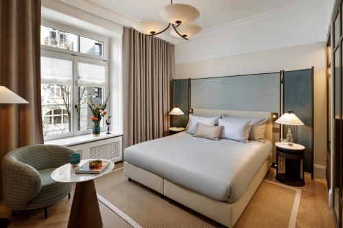 苏黎世苏黎世小型豪华大使酒店的一间卧室配有一张床、一把椅子和一张桌子