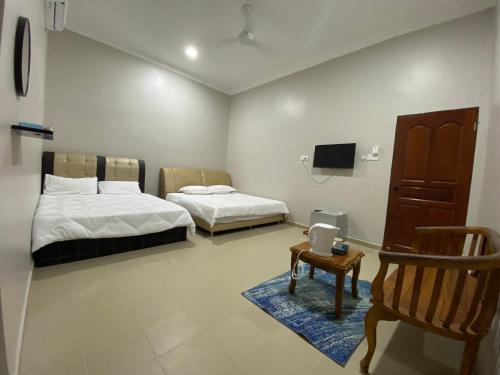 马兰Sasuka Guesthouse (Muslim Sahaja)的客房设有两张床、椅子和电视。