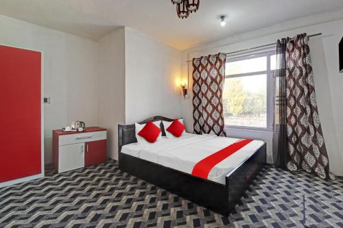 JawāharnagarEco Rooms的一间卧室配有一张带红色枕头的床和一扇窗户