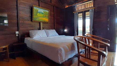 塔巴南The Bocah Desa Village的木制客房内的一间卧室,配有一张床