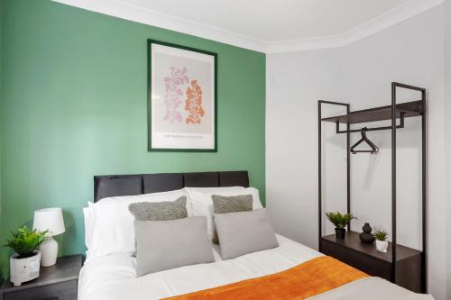 切姆Hidden Gem with Large Driveway, Comfortable Beds, Netflix, and Expansive Garden!的卧室拥有绿色和白色的墙壁,配有一张床