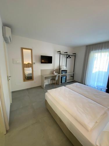 托尔博莱B&B Garda Home的白色卧室配有一张大床和一张书桌