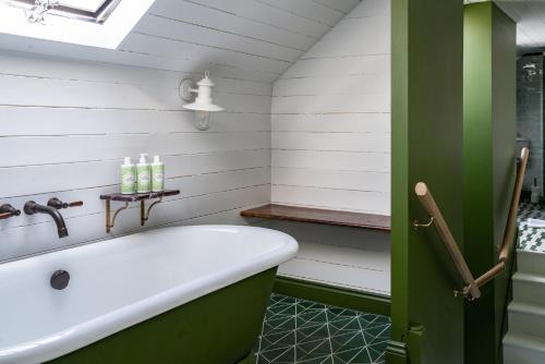 克兰菲尔德The Double Red Duke, Cotswolds的一间带白色浴缸和绿色门的浴室