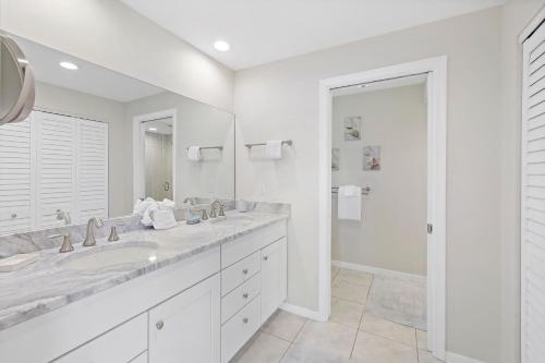 马可岛152 Leeward Court的白色的浴室设有两个盥洗盆和大镜子
