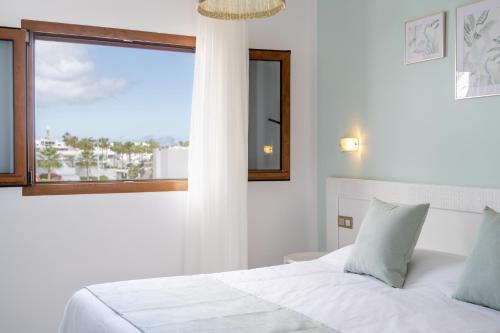 卡门港罗伯士岛成人公寓的卧室配有白色的床和窗户。