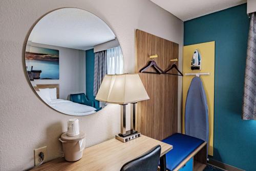 布伦瑞克布伦瑞克戴斯酒店的一间设有镜子和一张带台灯的桌子的房间