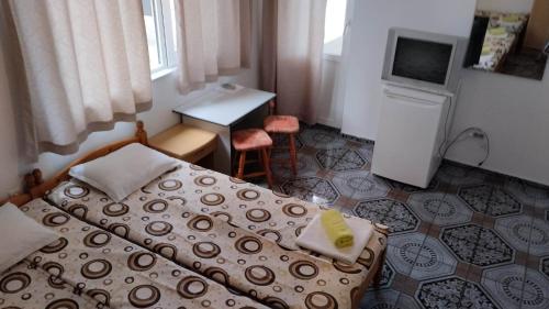 拉夫达стаи за гости Росица的一间卧室配有两张床、一张桌子和一台电视。