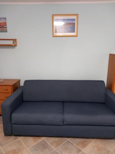圣托斯特凡诺港Residence Sole Dell'Argentario的墙上挂着照片的房间的蓝色沙发