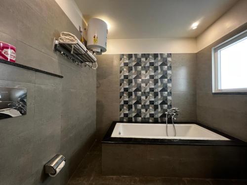 德拉敦HOTEL JS SOUVENIR的带浴缸的浴室和窗户。