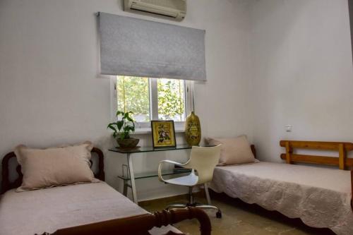 萨拉米斯Μονοκατοικία δίπλα στην Θάλασσα的一间卧室设有两张床、一张桌子和一个窗口。