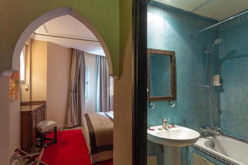 马拉喀什Le Caspien Boutique Hotel的一间带水槽和浴缸的浴室以及一张床