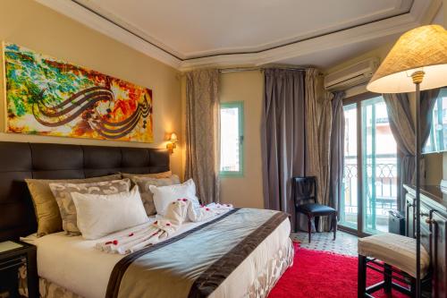 马拉喀什Le Caspien Boutique Hotel的卧室配有一张大床,墙上挂有绘画作品