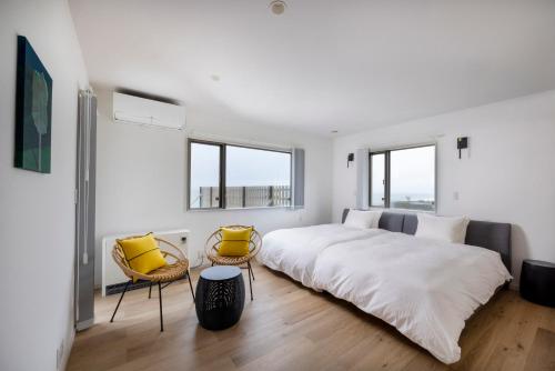 Izumo HOTEL THE CLIFF的白色卧室配有一张大床和两把椅子