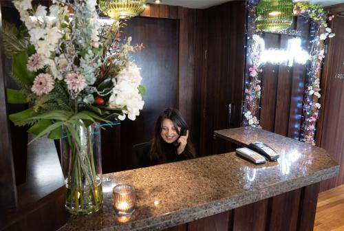 昆斯费里奥拉科码头酒店的坐在花瓶旁的柜台上的女人