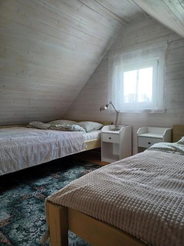 FilipówDomki skowronki的阁楼卧室设有两张床和窗户。