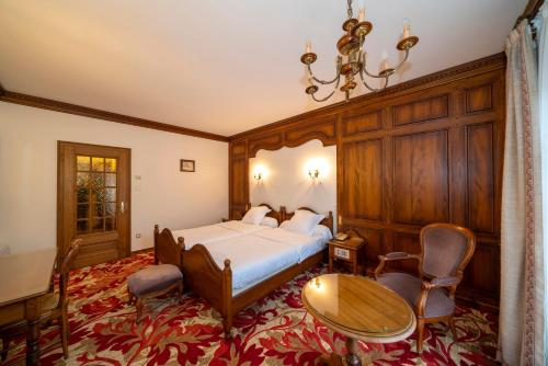 圣伊波利特Hotel Munsch Restaurant & Wellness, Colmar Nord - Haut-Koenigsbourg的卧室配有一张床和一张桌子及椅子