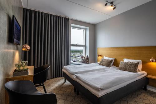 奥尔堡奥尔堡机场酒店的配有一张床、一张书桌和一扇窗户的酒店客房