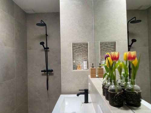 阿纳姆Appartement Osso Arnhem的浴室设有水槽和玻璃花瓶中的鲜花