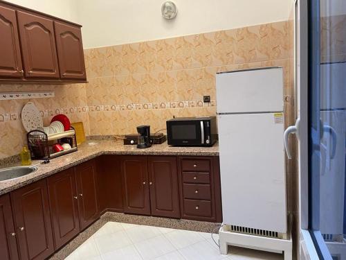 塞拉Holiday house的厨房配有棕色橱柜和白色冰箱