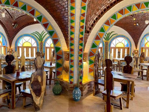 阿斯旺Kato Dool Wellness Resort的餐厅设有木桌和色彩缤纷的墙壁