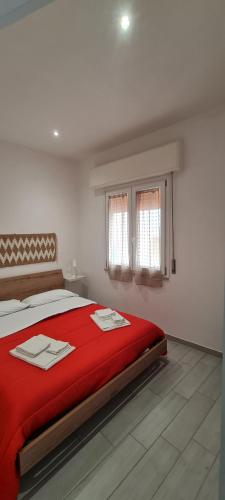 特拉帕尼La Siciliana Trapani Apartment的一间卧室配有一张带红色毯子的床和两个窗户