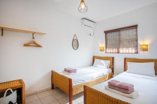 威廉斯塔德TUK Tropical Boutique Resort Jan Thiel的客房设有两张床、一张桌子和一扇窗户。
