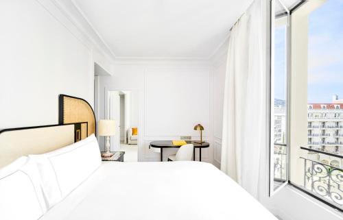 戛纳Carlton Cannes, a Regent Hotel的一间白色卧室,配有床和阳台