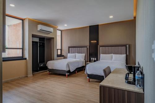 梅里达Hotel Kavia Premium - Paseo Montejo的酒店客房设有两张床和电视。