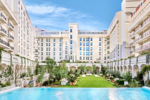 戛纳Carlton Cannes, a Regent Hotel的一座带游泳池的建筑的庭院的图象