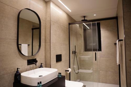 斯利马The Londoner Hotel Sliema的一间带水槽、镜子和淋浴的浴室